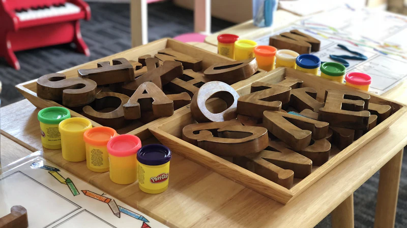 Wooden alphabet letters and tubs of modeling clay on a classroom table