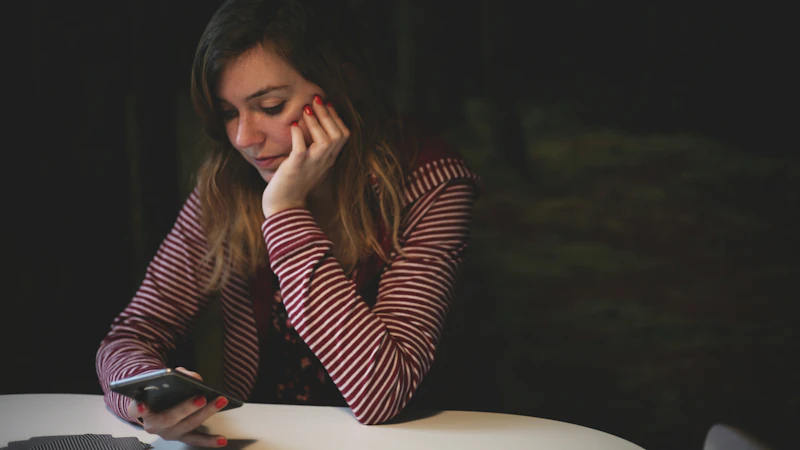 A woman reading on her smartphone late at night at a table