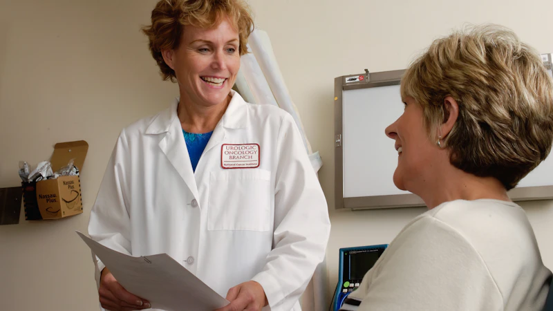 A smiling doctor in a white coat speaking with a patient in a clinic